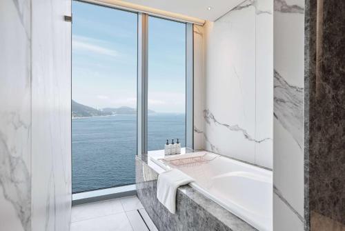a bathroom with a tub and a large window at Wyndham Grand Busan in Busan