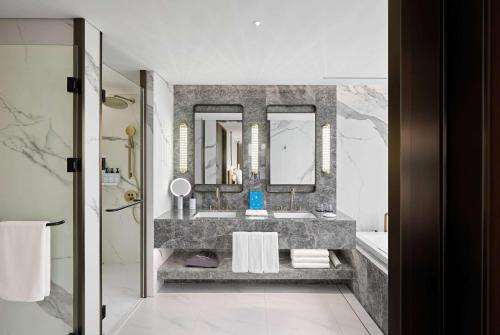 a bathroom with a sink and two mirrors at Wyndham Grand Busan in Busan