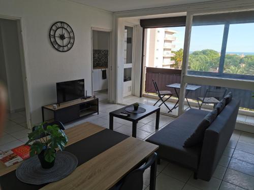 un salon avec un canapé et une table dans l'établissement Appartement refait à neuf, climatisé avec vue mer et montagne, avec place de parking privative, à Saint-Cyprien