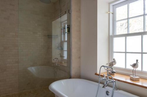 a bathroom with a tub and a shower and a sink at South Sands Hotel in Salcombe