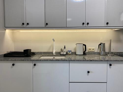 a kitchen with white cabinets and a counter top at CASA do CAMPO Lestrove in Padrón