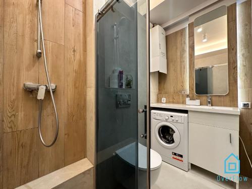 a bathroom with a shower and a washing machine at Anchor Apartment in Gdańsk