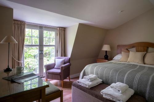 a bedroom with a bed and a chair and a window at South Sands Hotel in Salcombe