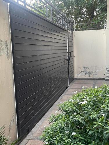 a black garage door with a gate and some bushes at Warraich villa gt raod gujrat entire in Gujrāt