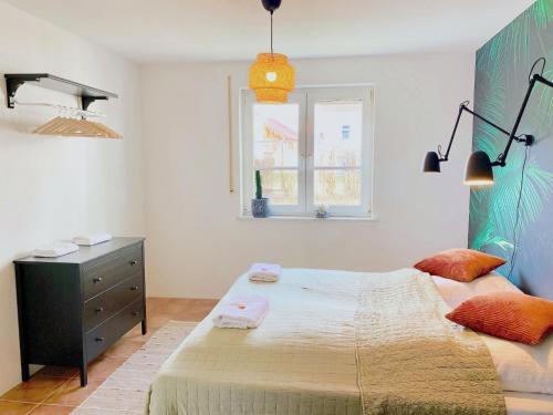 een slaapkamer met een bed, een dressoir en een raam bij Snug Stays I 3 Zimmer Design Apartment am See mit Garten I Home Office I Highspeed Wifi in Weßling