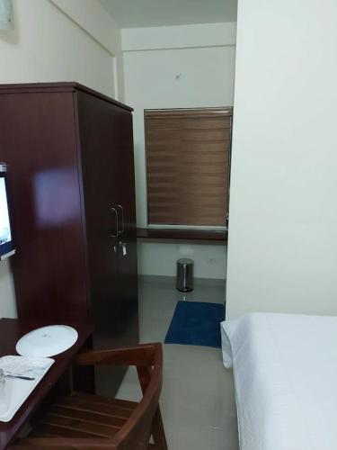 a room with a desk and a table and a chair at Masterkey Deluxe Rooms in Kakkanad