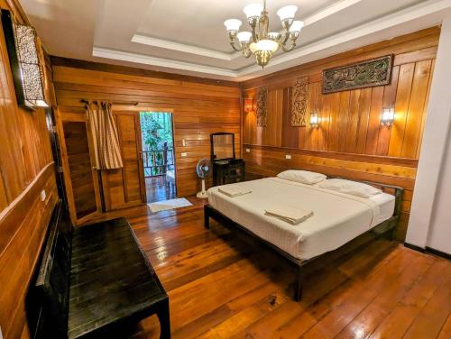 a bedroom with a bed and wooden walls and wooden floors at Ziggy Stardust in Ko Phayam