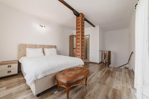a white bedroom with a bed and a stool at Cazare Zorilor in Zărneşti