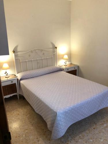 ein Schlafzimmer mit einem weißen Bett und zwei Nachttischen in der Unterkunft Alojamiento Mirasierra 2 in Torre del Campo