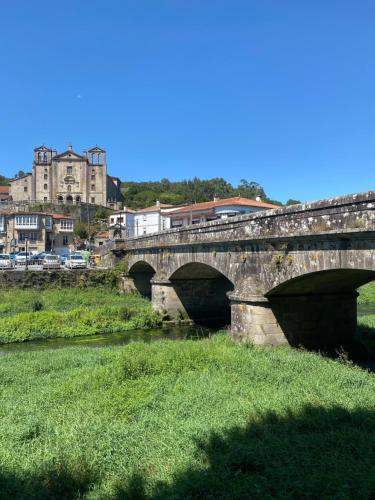 a bridge over a river with buildings in the background at CASA do CAMPO Lestrove in Padrón