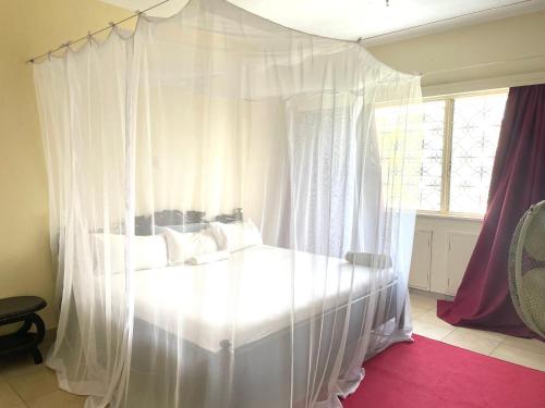 białe łóżko z baldachimem i białymi zasłonami w sypialni w obiekcie 2 Bedroom Sea View Apartment w mieście Mombasa