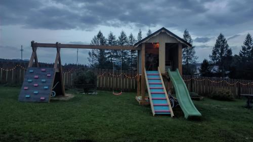 um parque infantil com escorrega e uma casa de brincar em Osada Sprzycka em Dzianisz