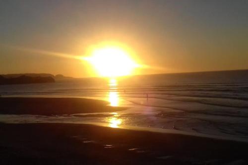 a sunset on the beach with the sun setting at Piso de Lujo en Salinas in Salinas