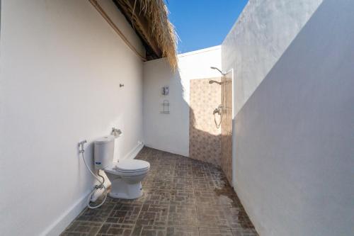 a bathroom with a toilet in a wall at brothers bungalows in Jimbaran