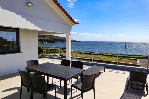 een patio met een tafel en stoelen en de oceaan bij Villas da Salga in Angra do Heroísmo