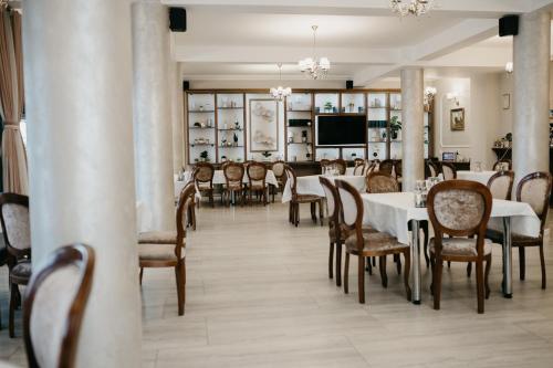 a dining room with tables and chairs and a tv at PENSIUNEA ANA in Piatra Neamţ