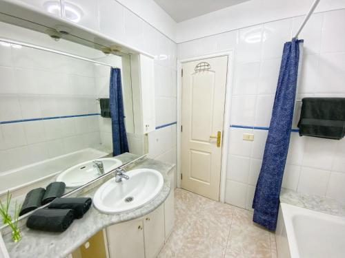 a bathroom with a sink and a tub and a mirror at Hugo's holiday apartment in Costa del Silencio in Arona