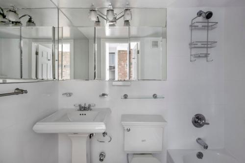 uma casa de banho com um lavatório, um WC e um espelho. em East Village 2br w wd nr union square NYC-1260 em Nova York