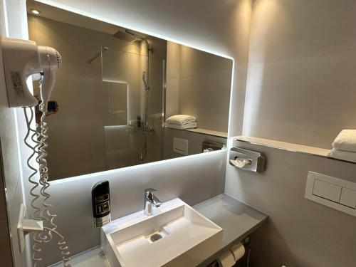 baño con lavabo y espejo grande en Hotel am Karlstor, en Karlsruhe