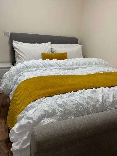 a large bed with a yellow blanket on it at Cosy room away from home in Yate