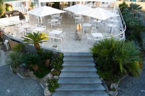 una escalera que conduce a un restaurante con mesas y sombrillas en Hotel Parco Delle Agavi en Ischia