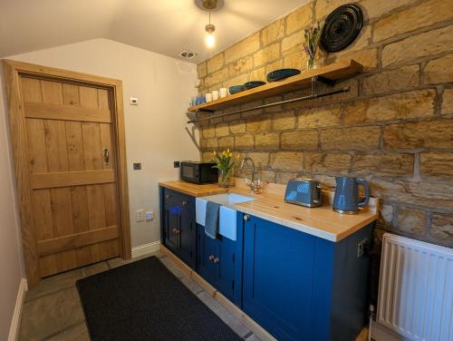 una cucina con armadi blu e un muro in pietra di The Pudding Stop - Bakewell - Free Parking a Bakewell