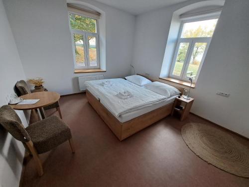 クラーリーキにあるHotel Poutní Důmのベッドルーム1室(ベッド1台、テーブル、窓2つ付)