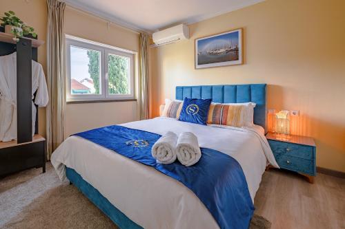 a bedroom with a blue and white bed with towels on it at Gold Coast Photography Inn in Estoril