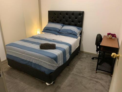 a bedroom with a bed with a blue comforter and a table at Summer Inn City Accommodation in Melbourne