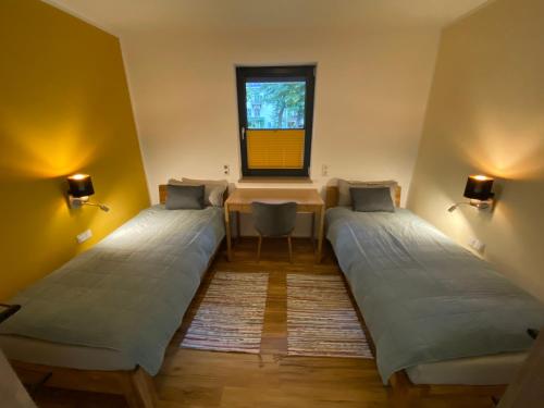 2 Betten in einem Zimmer mit einem Tisch und einem Fenster in der Unterkunft Rollstuhlgerechtes Ferienapartment A1 Villa Wilisch 65qm in Amtsberg