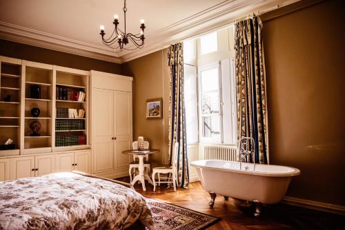 1 dormitorio con bañera, cama y ventana en Château de la Grange Moreau en Vallon-sur-Gée