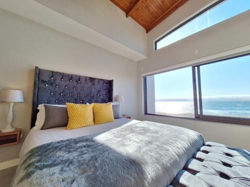 a bedroom with a large bed with a large window at Beyond Beautiful Beach House in Langstrand