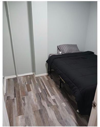um quarto com uma cama e piso em madeira em Cozy 2 bedrooms and a Yard em Brooklyn