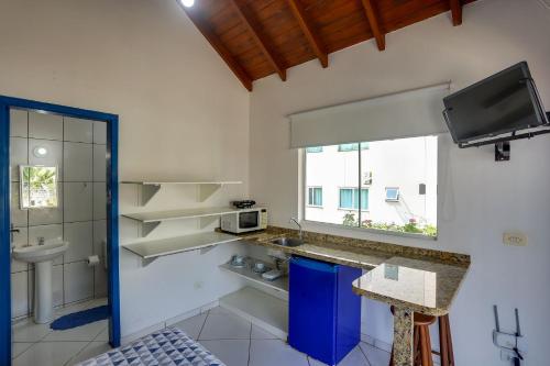 a white kitchen with a sink and a microwave at Pousada Canario Azul in Bombinhas