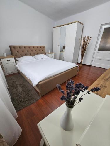 a bedroom with a bed and a vase of flowers on a table at Iosia Premium Apartment in Oradea