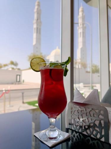 a drink in a glass with a lime on a table at Hill Top Muscat in Muscat