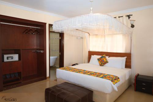 1 dormitorio con 1 cama blanca con dosel en Gatimene Gardens Hotel, en Meru