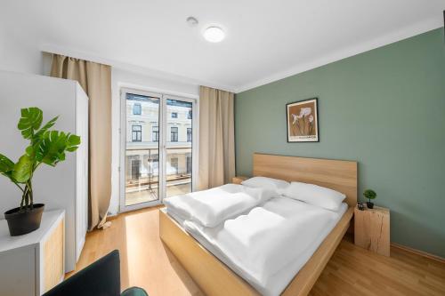 ein Schlafzimmer mit einem weißen Bett und einem großen Fenster in der Unterkunft Flora Collection in Wien