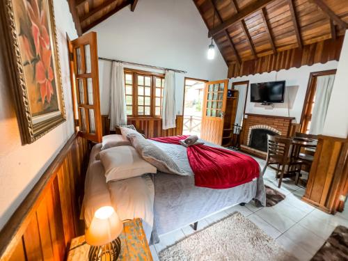 a bedroom with a bed and a living room with a fireplace at Estalagem Monte Verde in Monte Verde