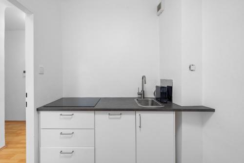 a kitchen with white cabinets and a sink at Flora Collection in Vienna
