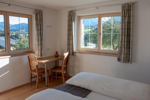 Schlafzimmer mit einem Bett, einem Tisch und Fenstern in der Unterkunft Ferienwohnung Kant in Fieberbrunn