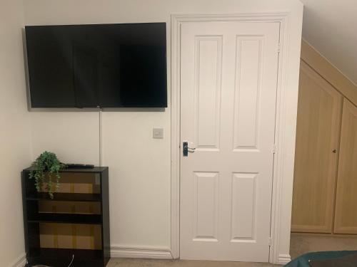 een witte deur met een flatscreen-tv aan een muur bij Comfy double Bedroom in Greater Manchester in Manchester