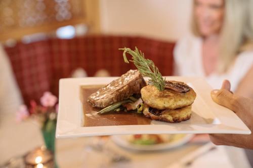 a person holding a plate of food on a table at Feriengut Unterhochstätt in Schwendt