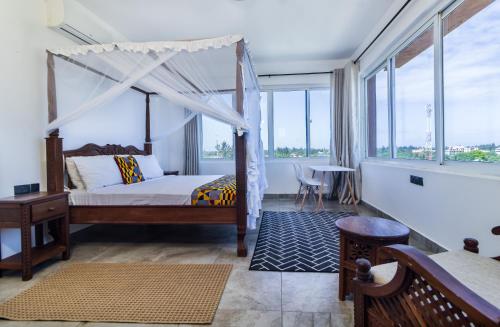 Schlafzimmer mit Himmelbett und großen Fenstern in der Unterkunft luzlux penthouse Diani in Ukunda
