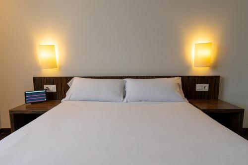 a bedroom with a large white bed with two lights at ETH Rioja in Haro