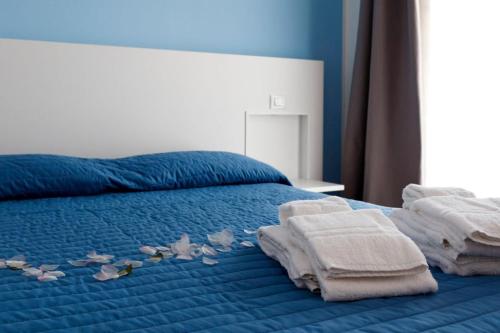 ein blaues Bett mit Handtüchern und Blumen darauf in der Unterkunft Casavacanzefranca - 12 in Terrasini