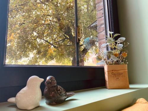 a window sill with a bird figurine and a plant at La Villa des Roses - Suite & Spa in Lys-lez Lannoy