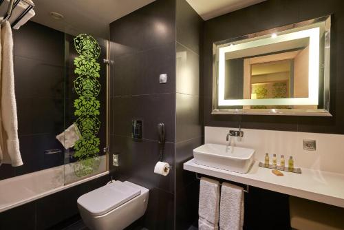 een badkamer met een toilet, een wastafel en een spiegel bij DoubleTree by Hilton Girona in Girona