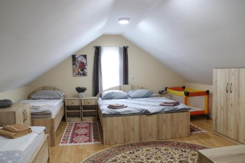 Cette chambre mansardée comprend 2 lits et une fenêtre. dans l'établissement Vila Tamaškut, à Lendava