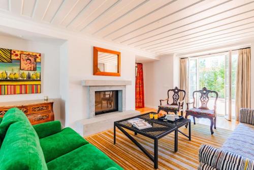 a living room with a green couch and a fireplace at Villa Azzurra Cascais 5BR in Cascais